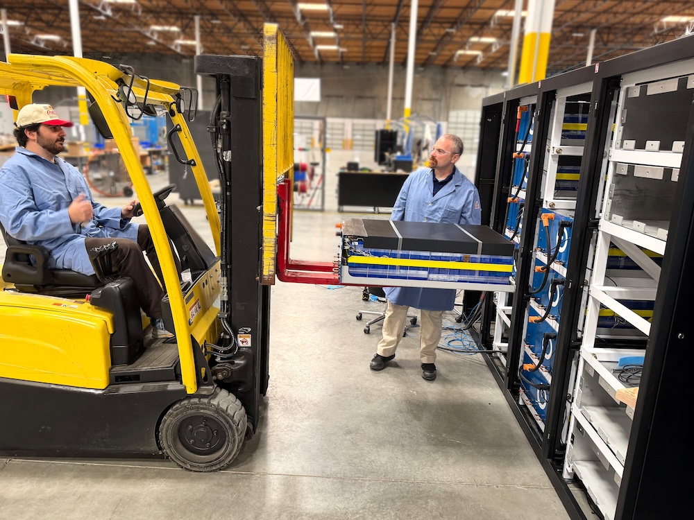 Two sparkz employees building the Qube560 with a forklift